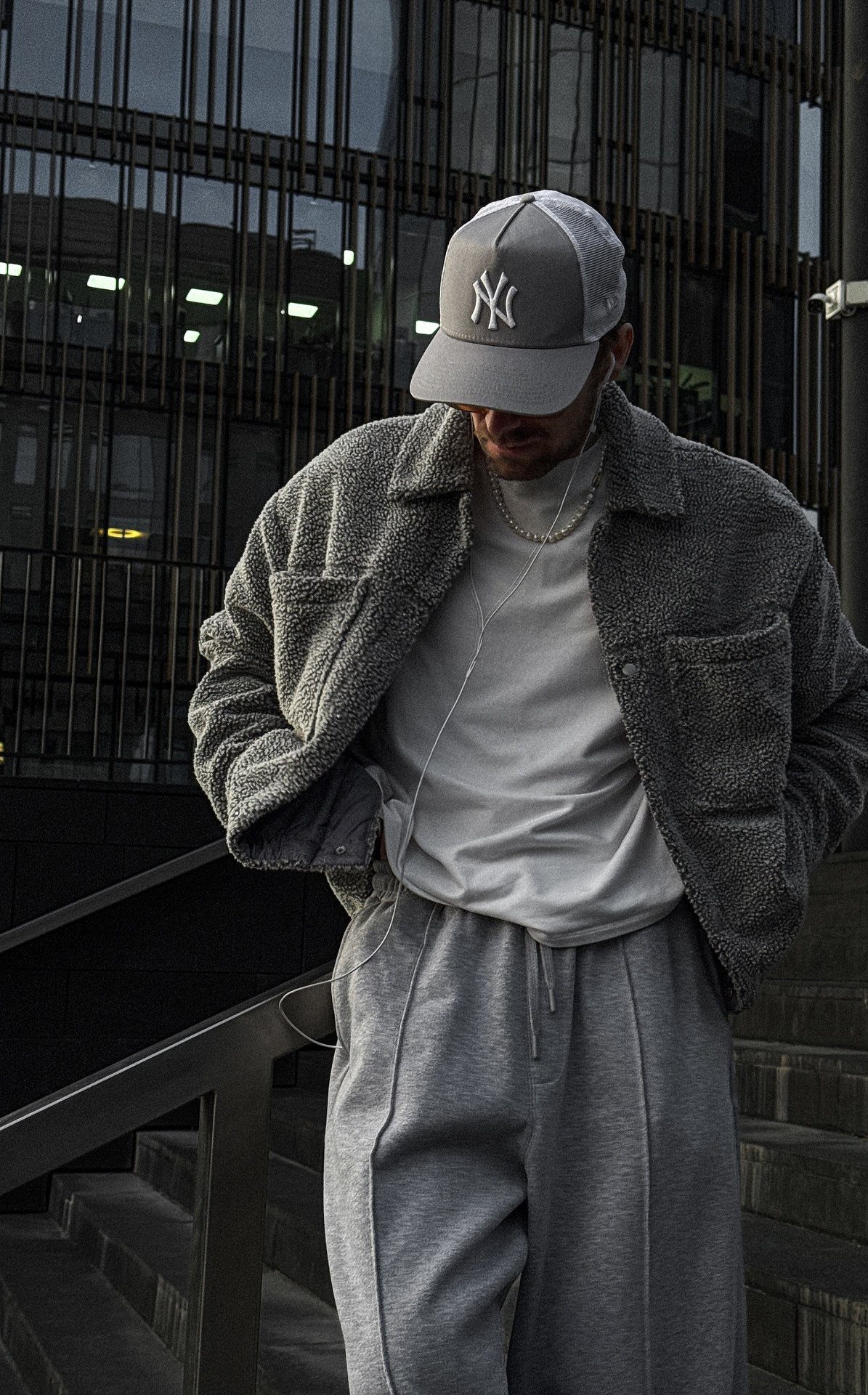 Person in grey fleece jacket and sweatpants wearing a grey baseball cap outdoors.
