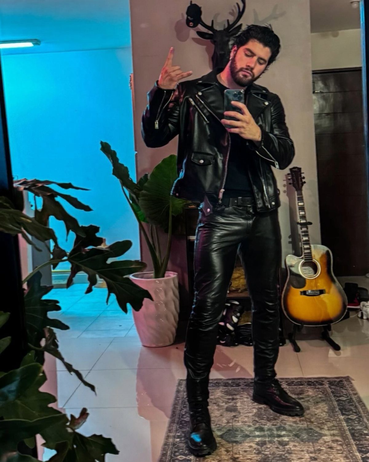 Man in all-black leather outfit including biker jacket and pants taking a selfie