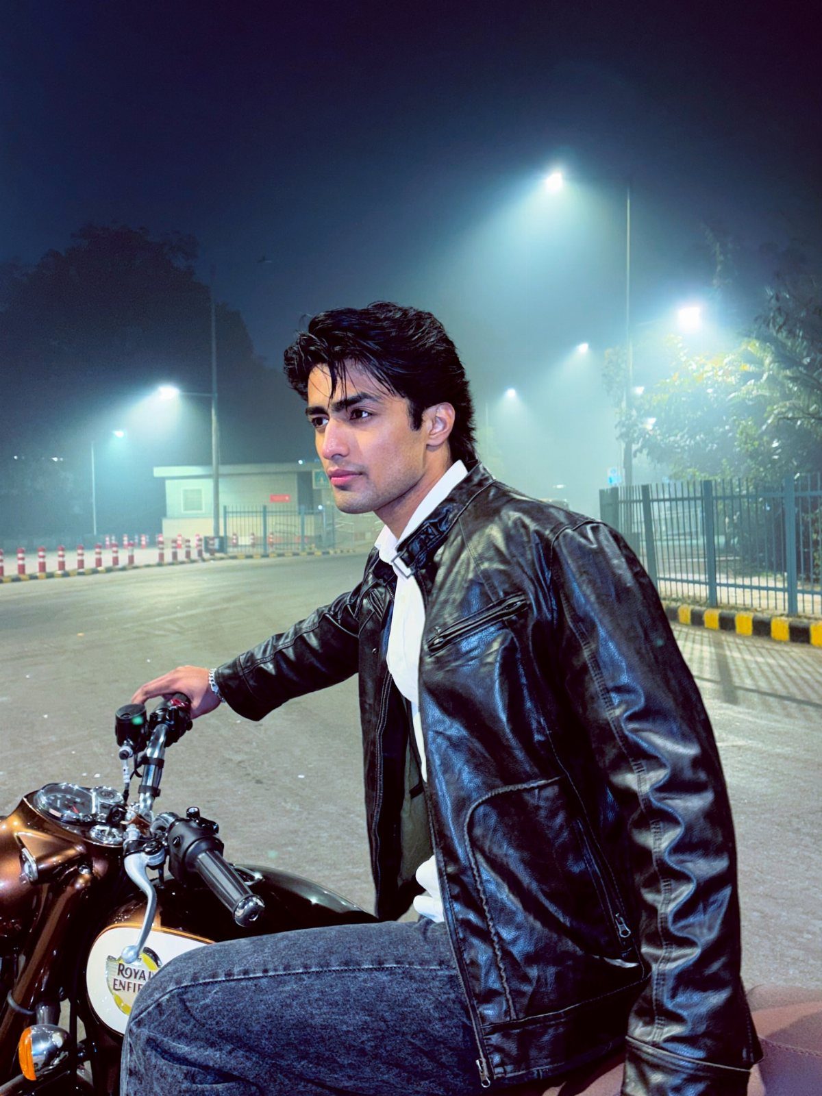 Man in black leather jacket and white shirt sitting on a brown motorcycle