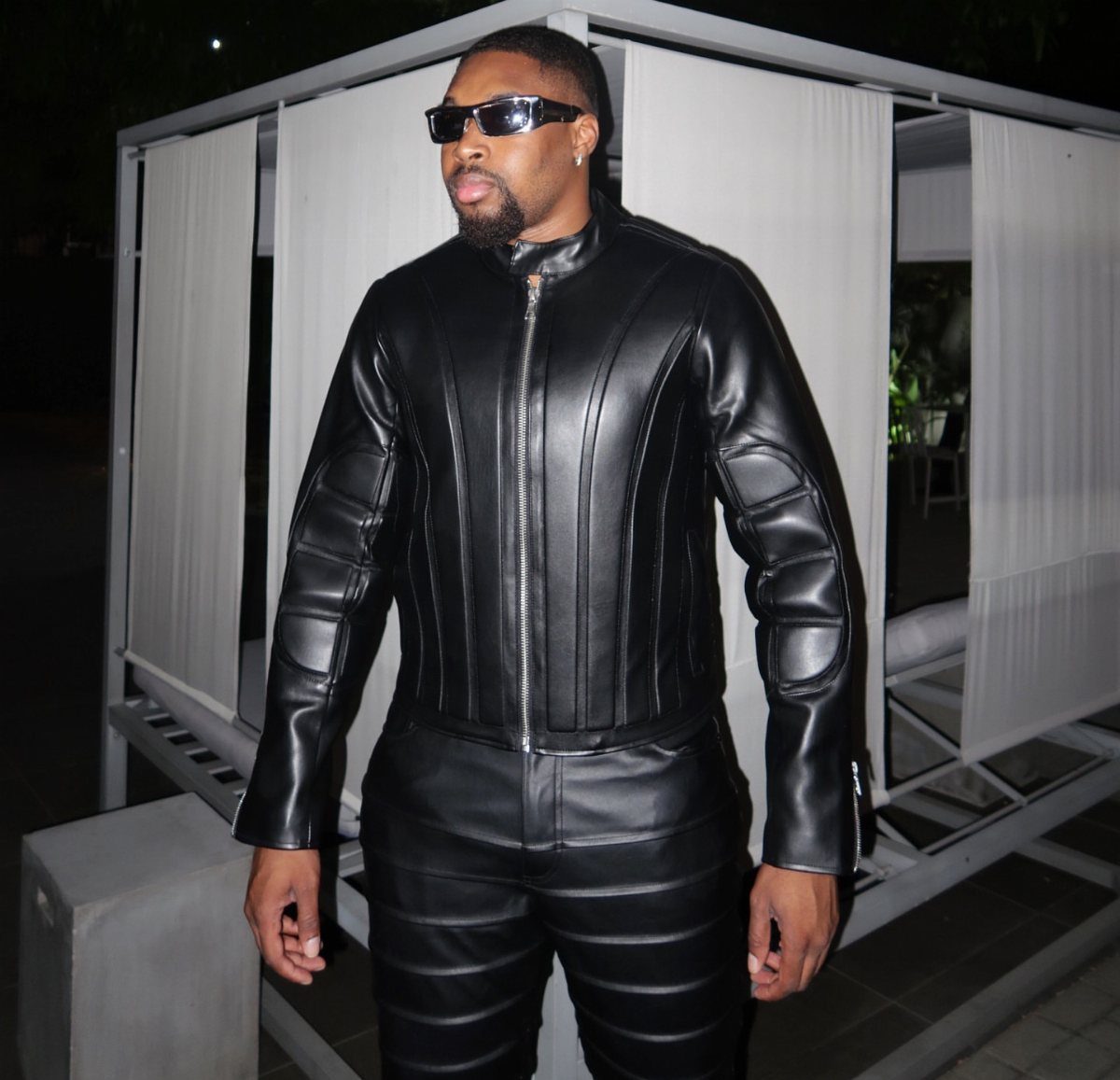 Man in a black leather jacket and matching leather trousers wearing black sunglasses.