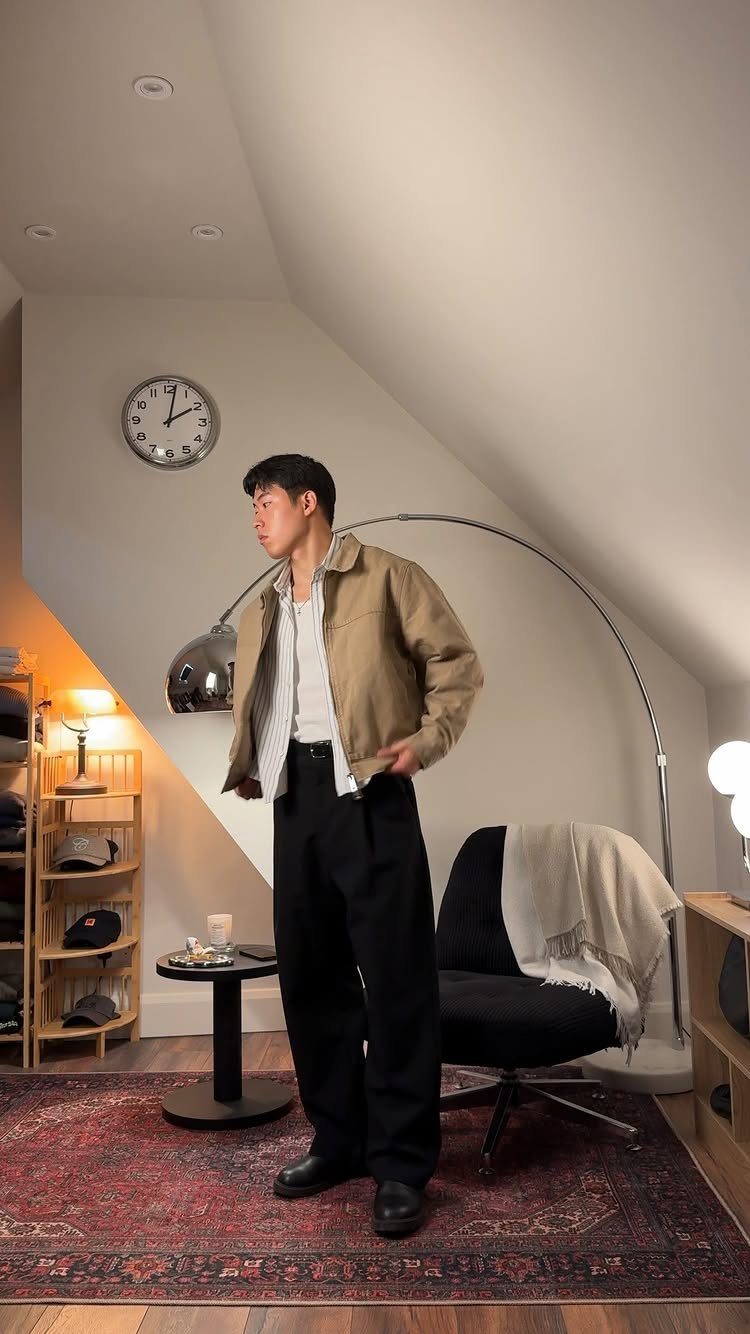 Man wearing a tan corduroy jacket and black trousers in a modern room.