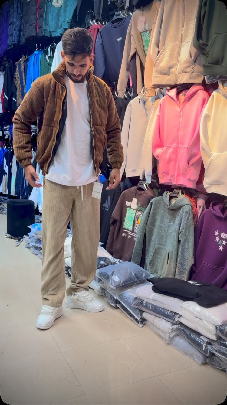 Man wearing a brown corduroy jacket and beige corduroy sweatpants in a clothing store