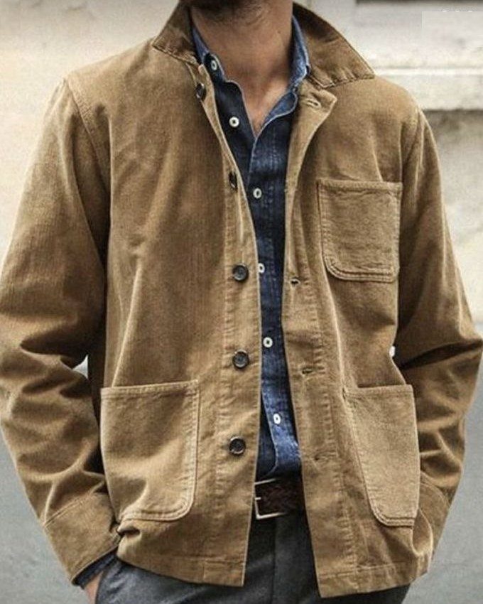 Brown corduroy jacket worn over a blue button-down shirt and grey trousers.