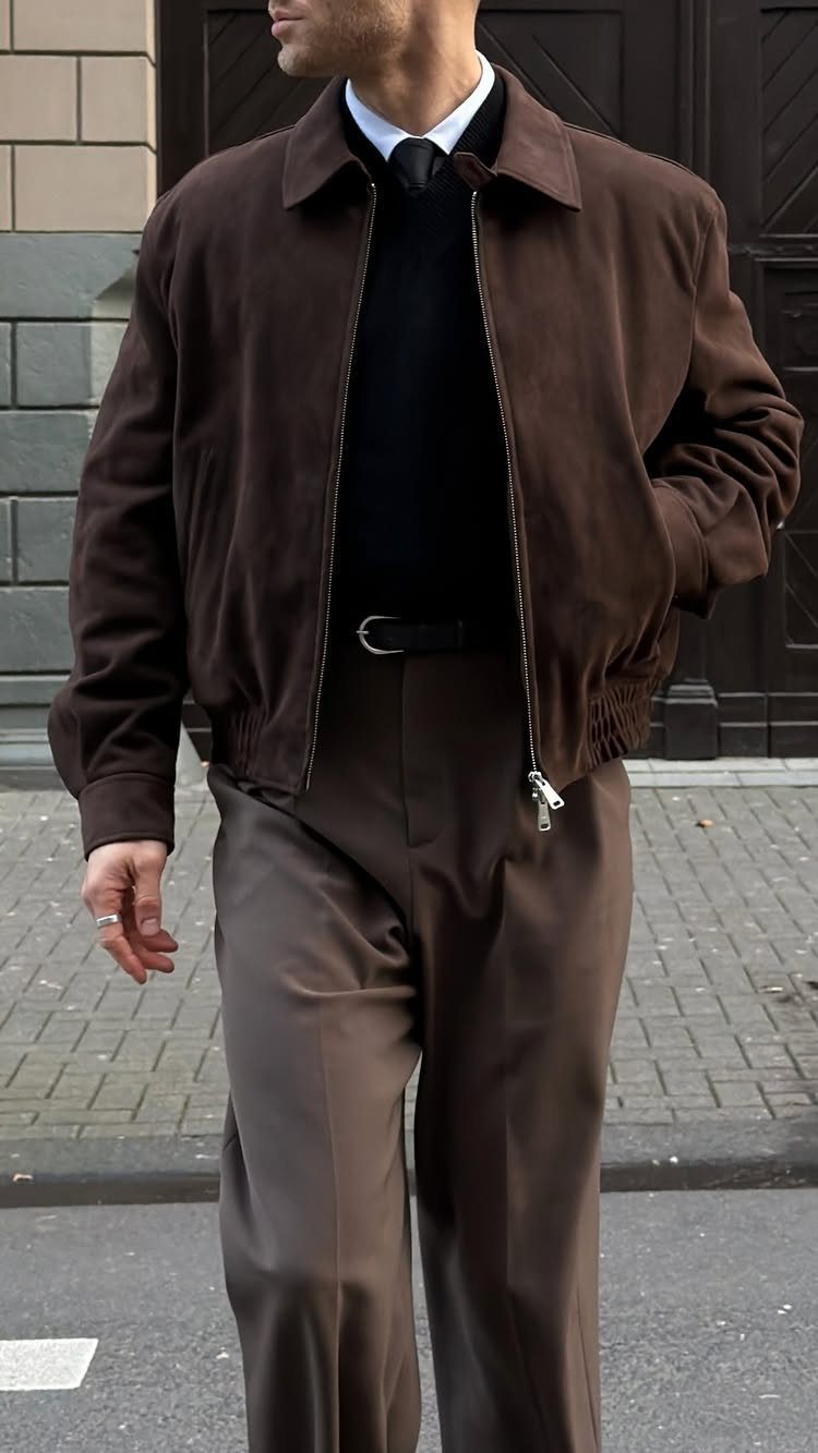 Man wearing a brown suede jacket with a black sweater and brown trousers.