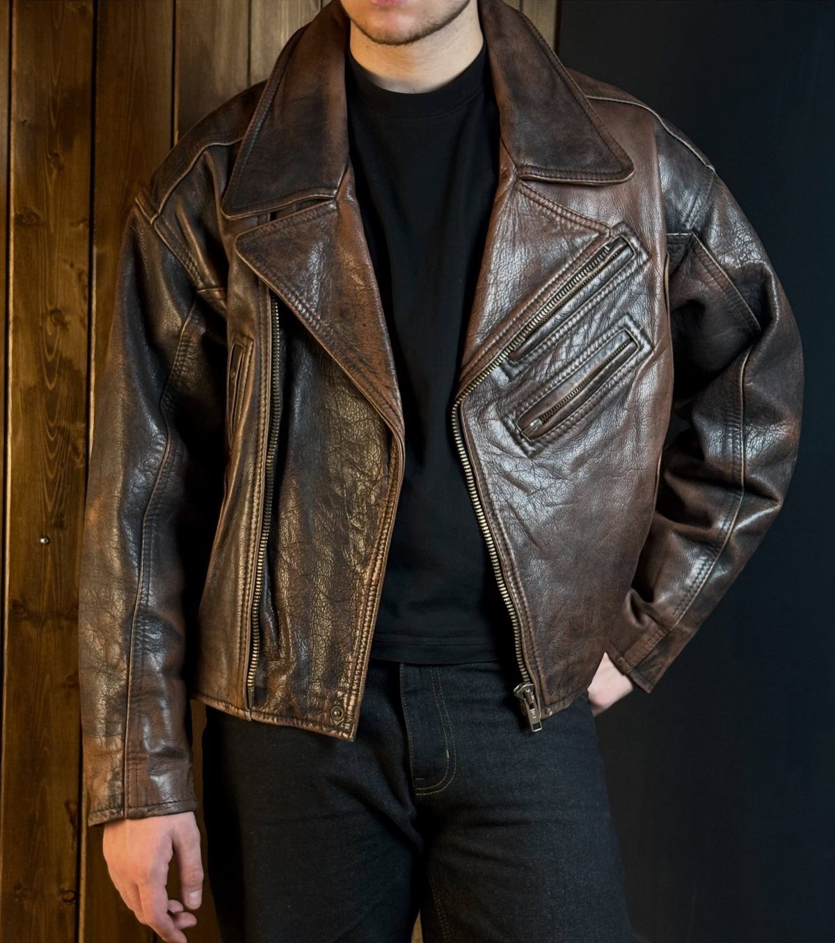 Person wearing a distressed brown leather biker jacket with black t-shirt and jeans.