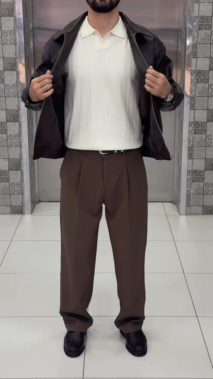 Man wearing a dark brown leather jacket, white polo, and brown trousers.