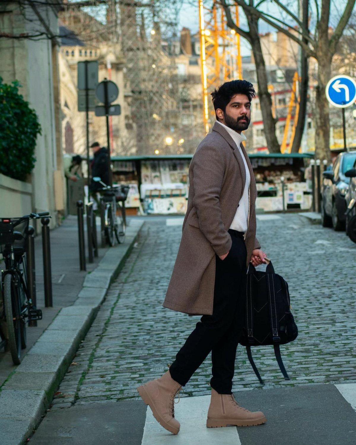 Man in brown wool coat and black trousers walking on cobblestone street