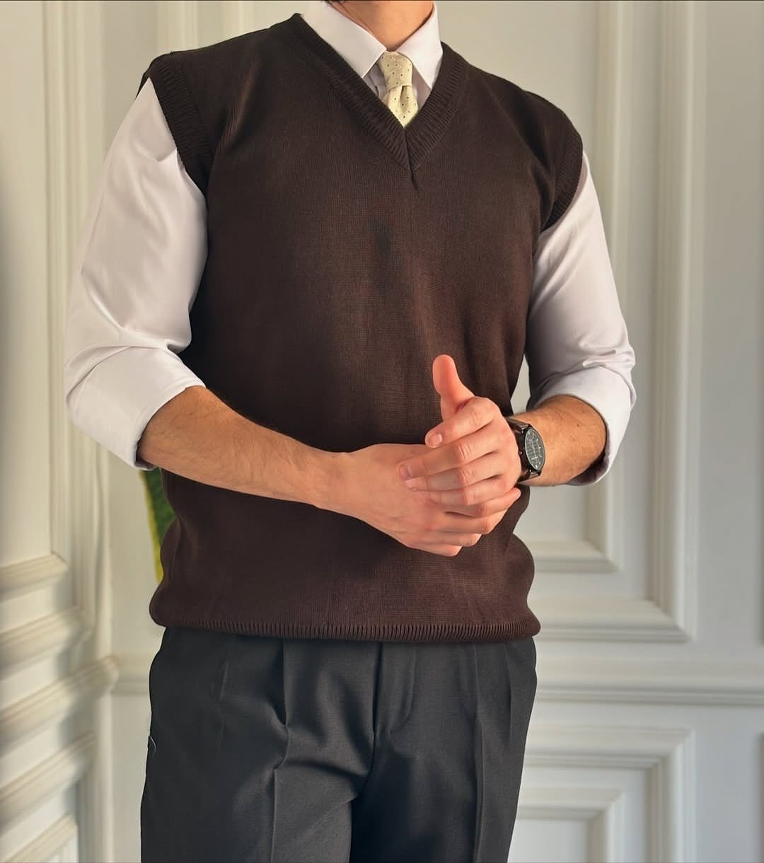 Man wearing a brown sweater vest, white shirt, gold tie, and charcoal dress pants.