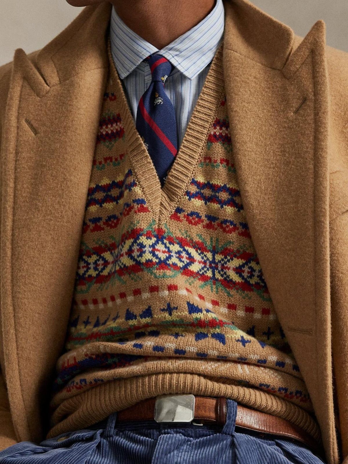 Camel wool coat worn over a tan Fair Isle sweater and blue corduroy trousers.