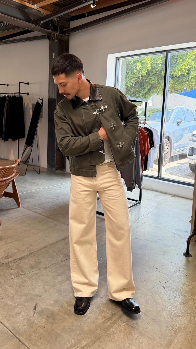 Man wearing olive green jacket and wide-leg cream trousers in a clothing store.