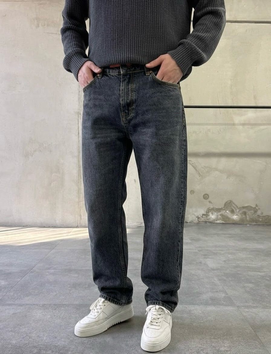Person wearing dark wash straight-leg jeans, a grey sweater, and white sneakers.