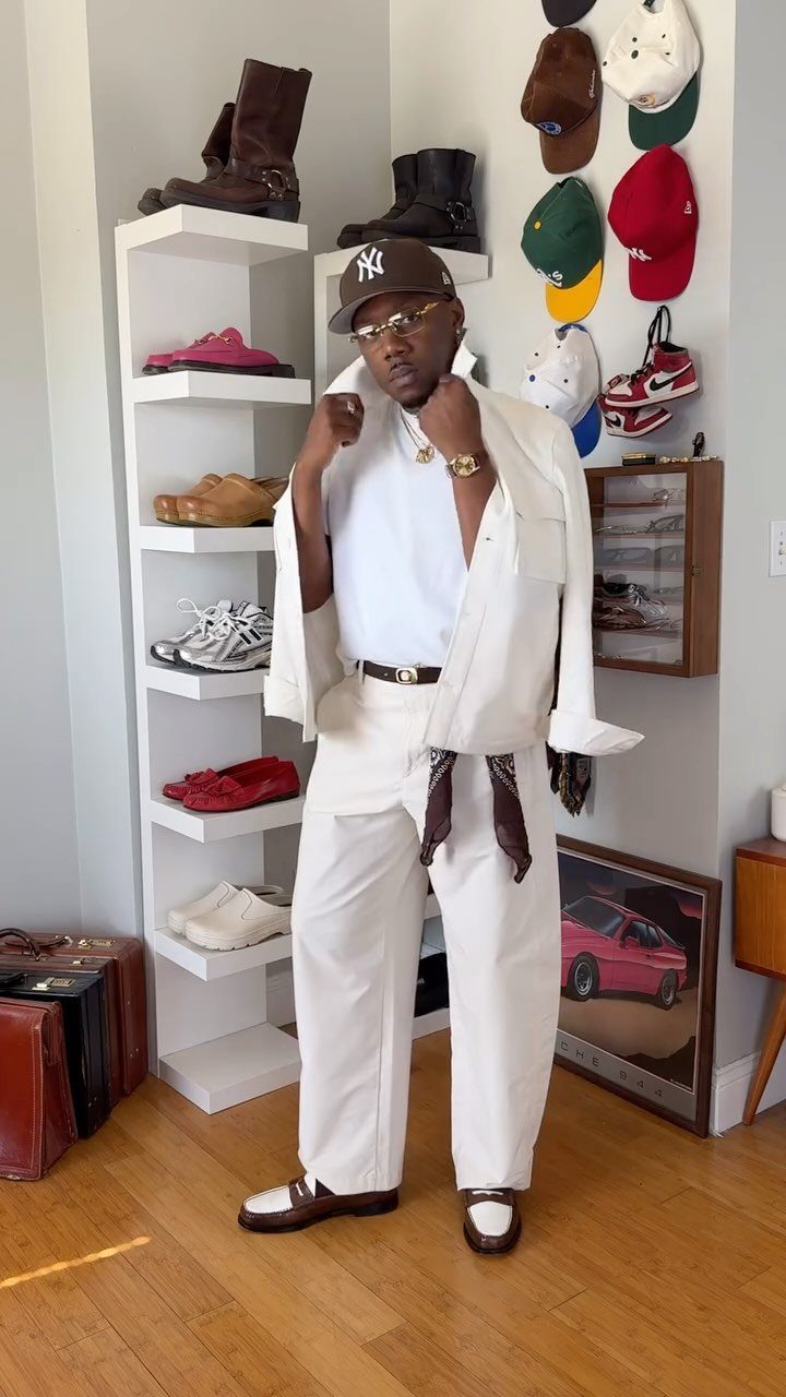 Man in all-white layered spring outfit with a dark baseball cap and shoes.