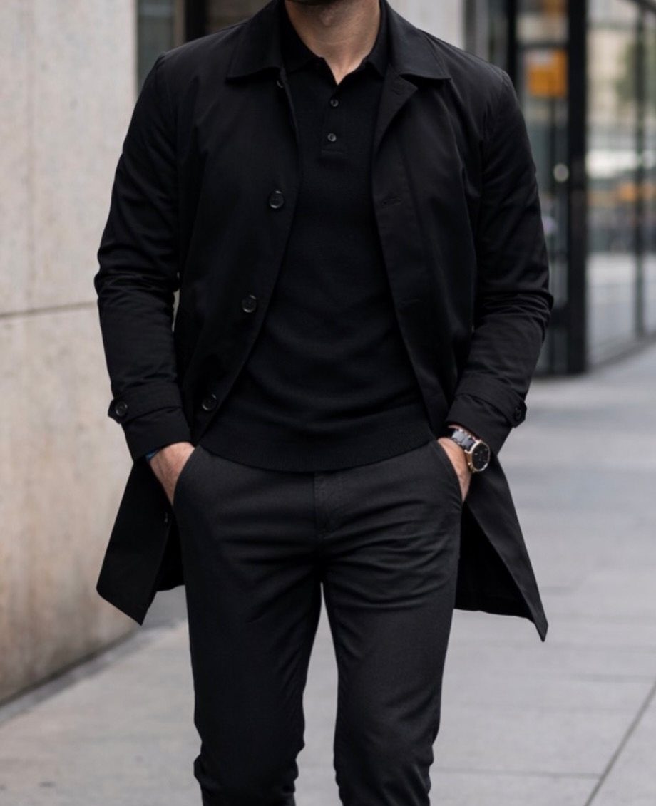 Man in all-black outfit wearing a black trench coat on a city street