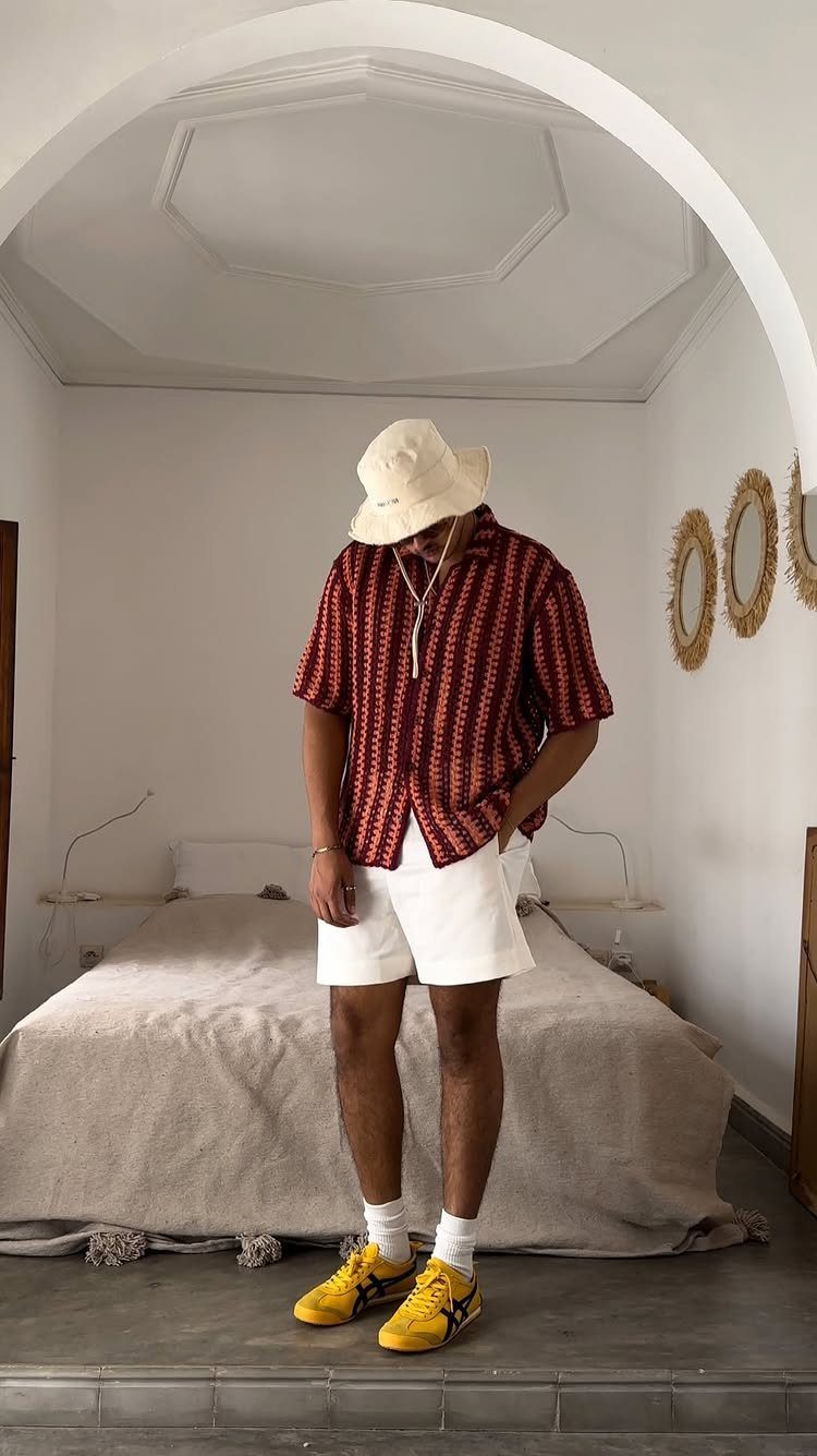 Person in striped short-sleeve button-down shirt, white shorts, and yellow sneakers indoors.