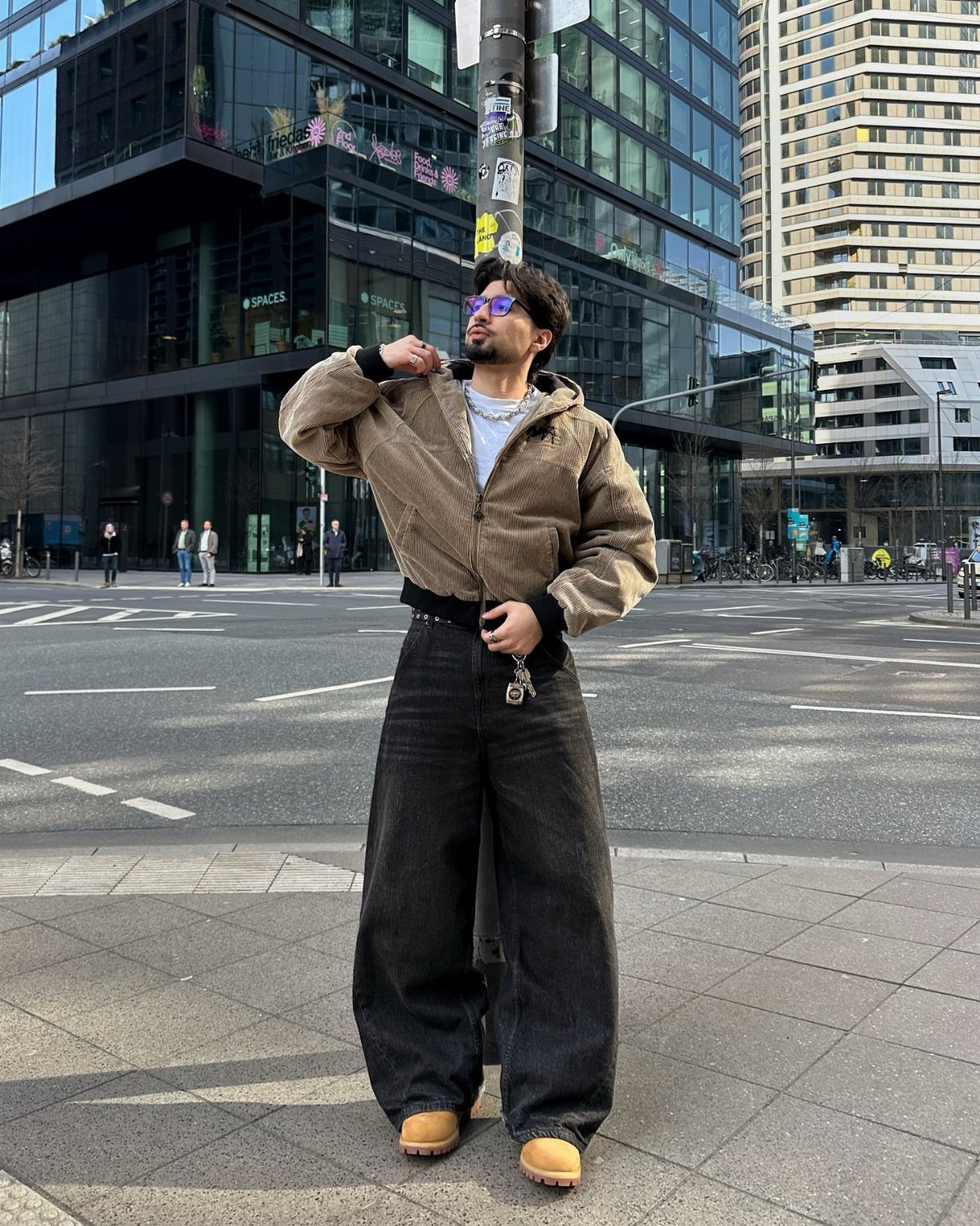 Person wearing a tan cropped corduroy jacket and wide-leg black trousers on city street