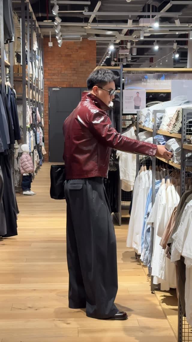 Person wearing a cropped red leather jacket and wide-leg black trousers in a store.