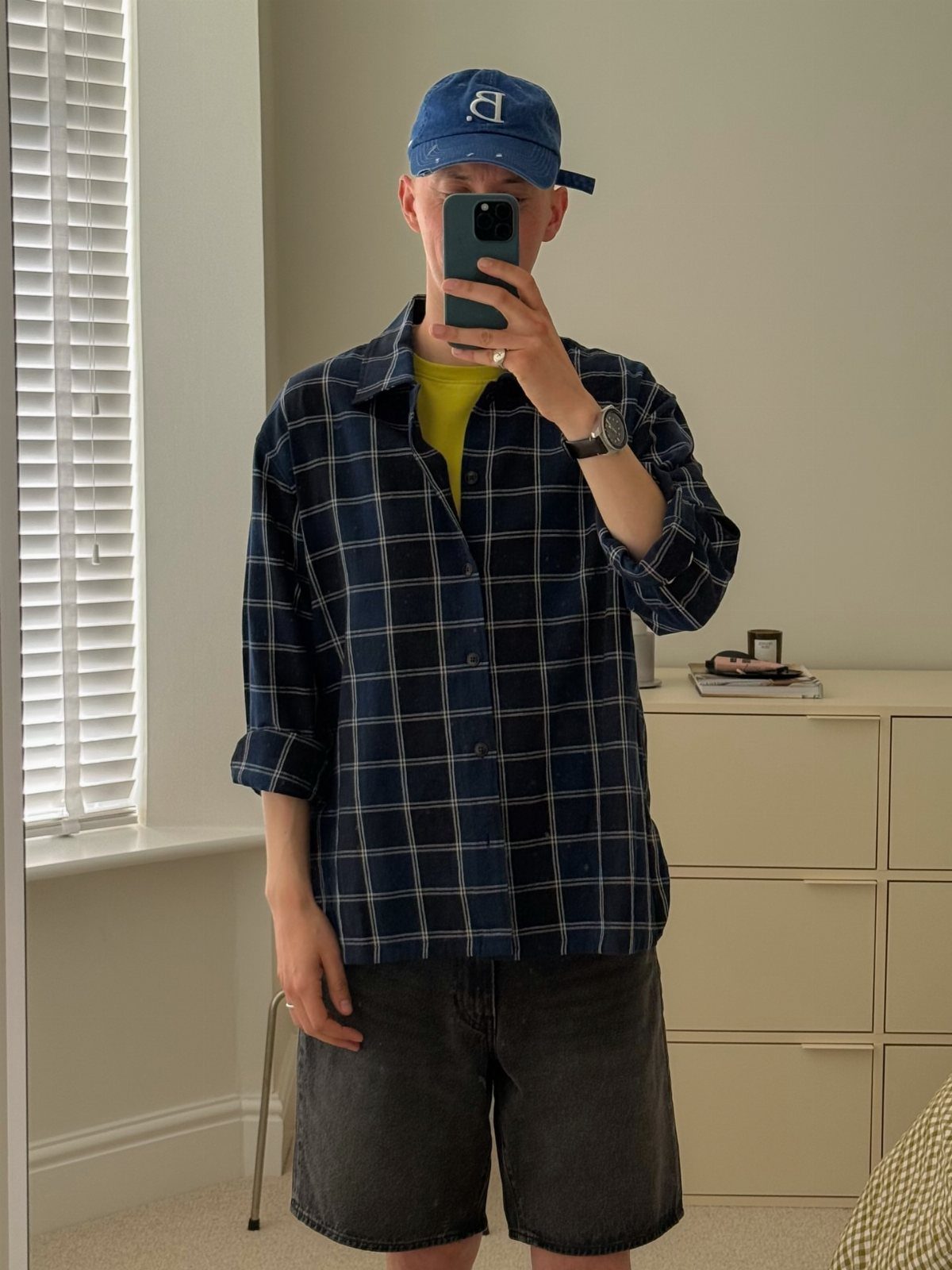 Man in a blue checkered shirt, yellow t-shirt, and blue baseball cap.