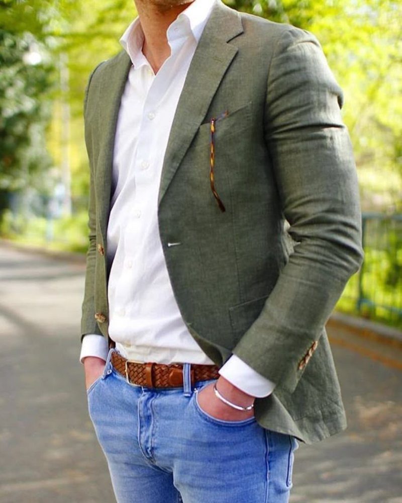 Man in olive green linen blazer, white shirt, and light blue jeans outdoors.