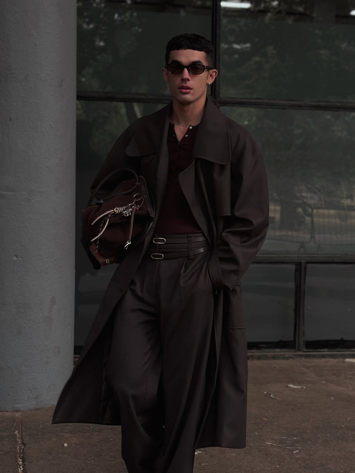 Man in a dark brown trench coat and matching brown trousers with sunglasses