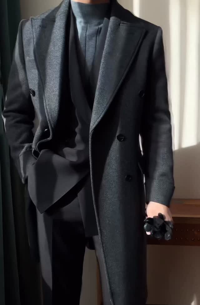 Man wearing a dark grey double-breasted overcoat with a matching suit and turtleneck.