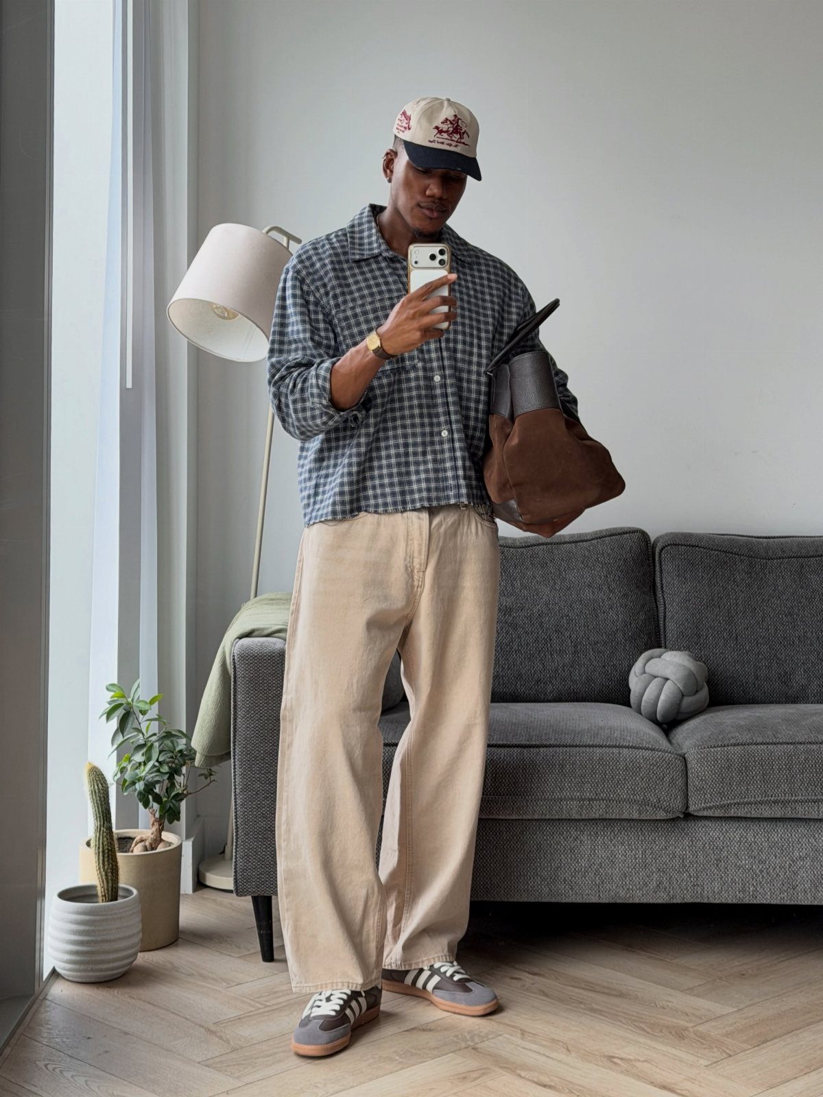 Man wearing a checkered shirt and beige trousers for a fall outfit.
