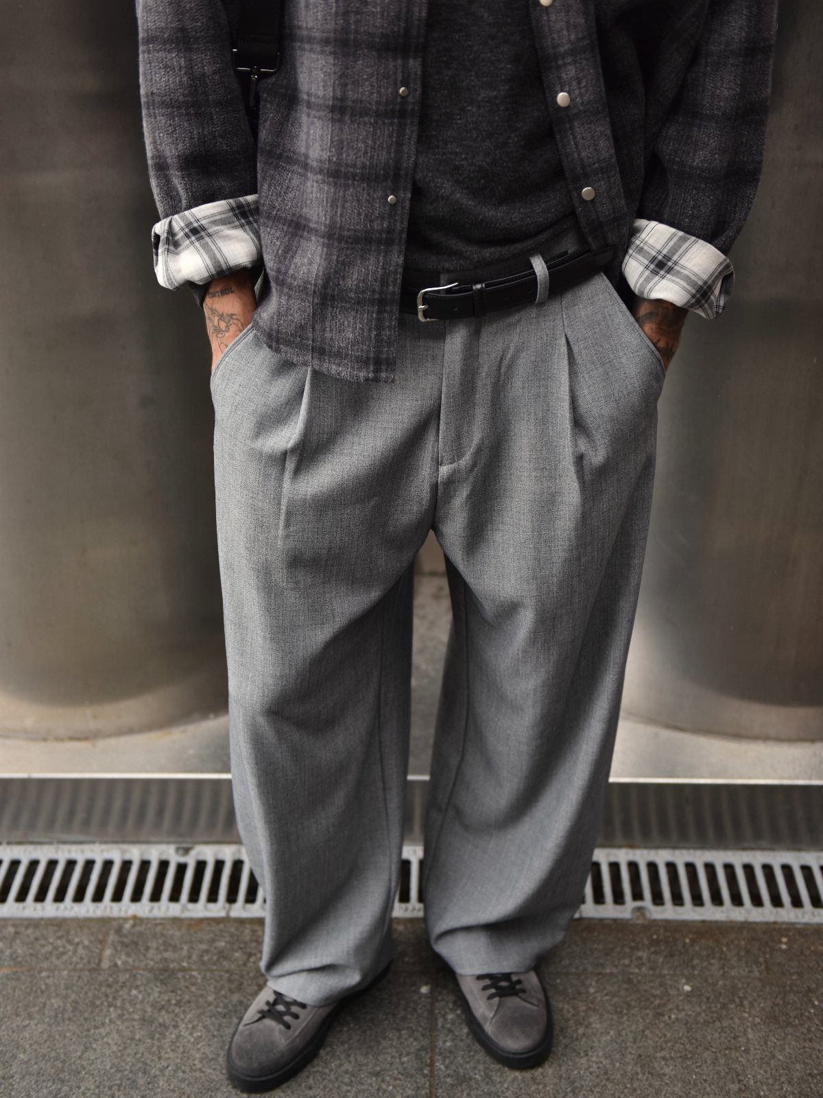 Gray flannel trousers with pleats paired with a plaid shirt and suede shoes.
