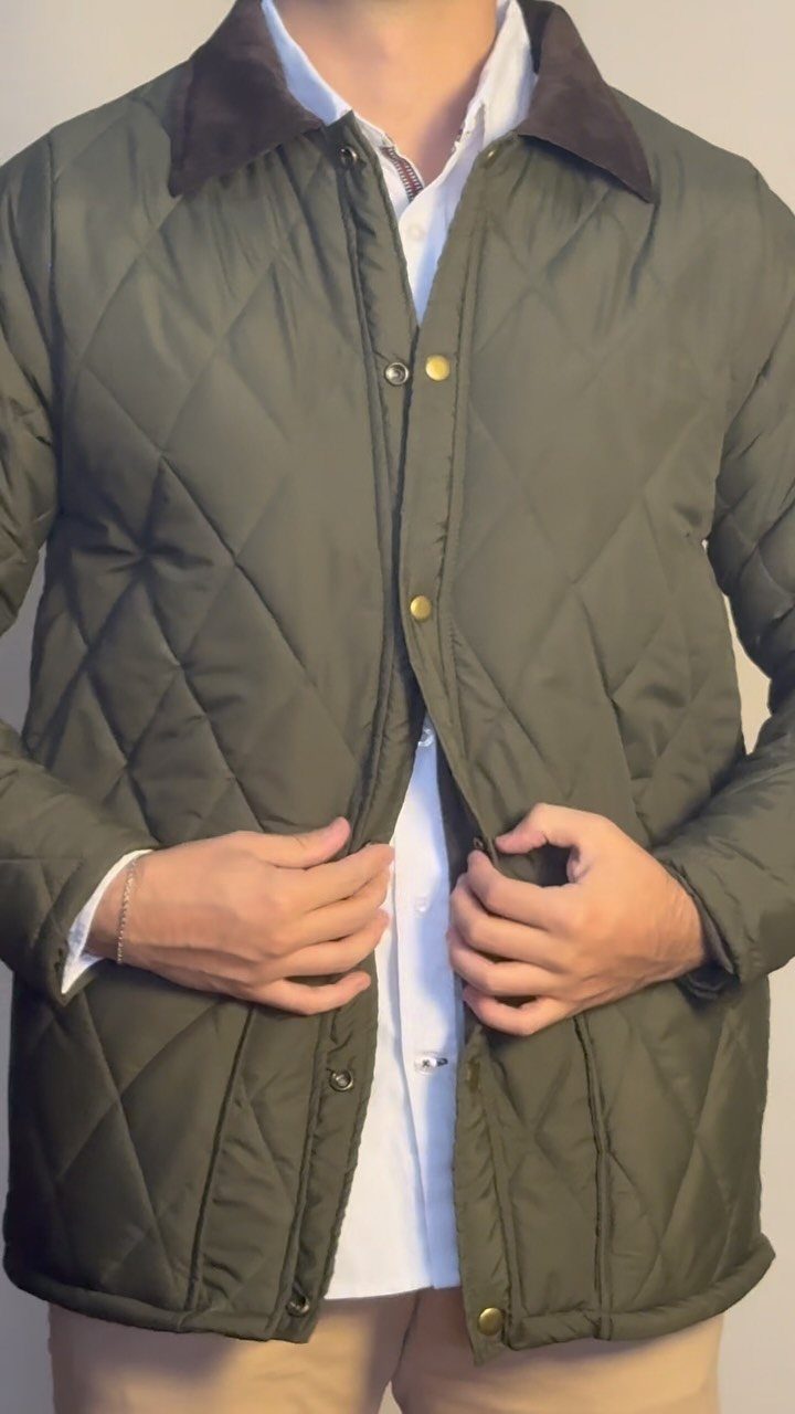 Olive green quilted jacket with brown collar worn over a white shirt.