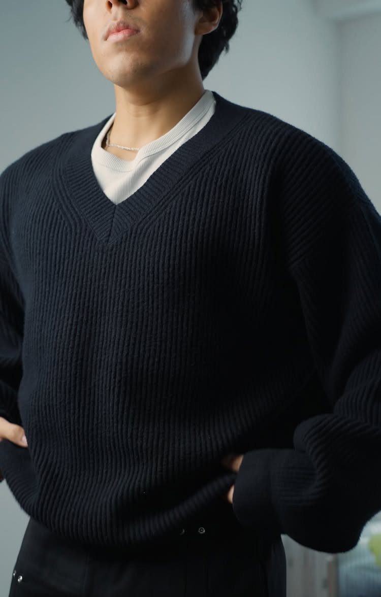 Person wearing a black ribbed V-neck sweater over a white t-shirt.