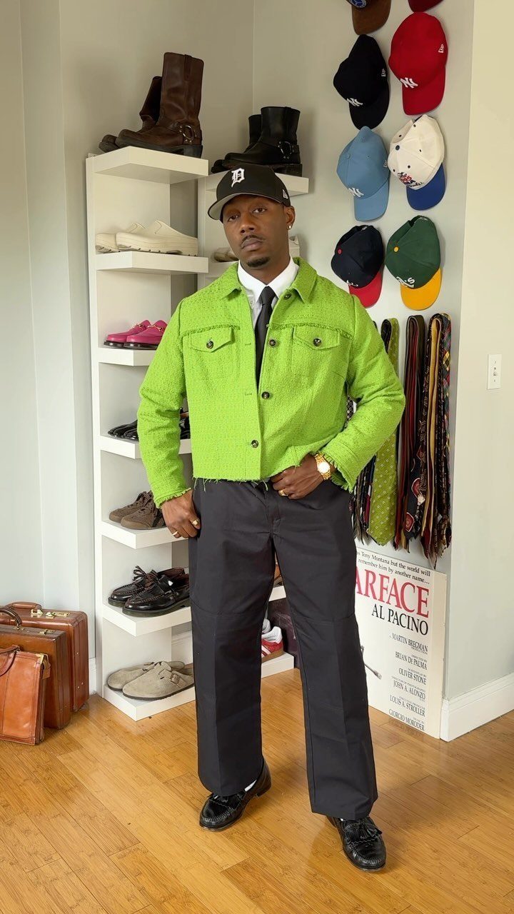 Man wearing a bright lime green jacket, black trousers, and a black cap.