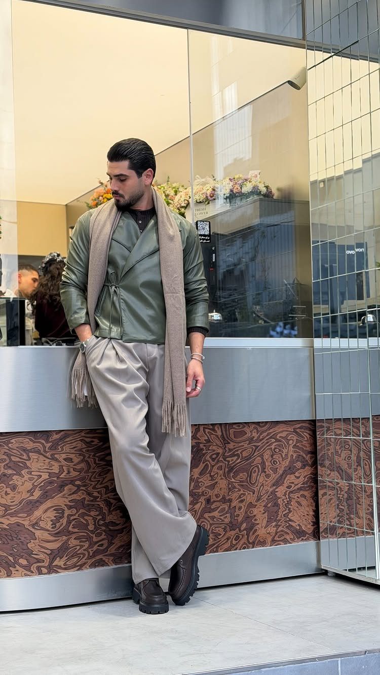 Man wearing an olive green wrap jacket with beige trousers and a scarf.