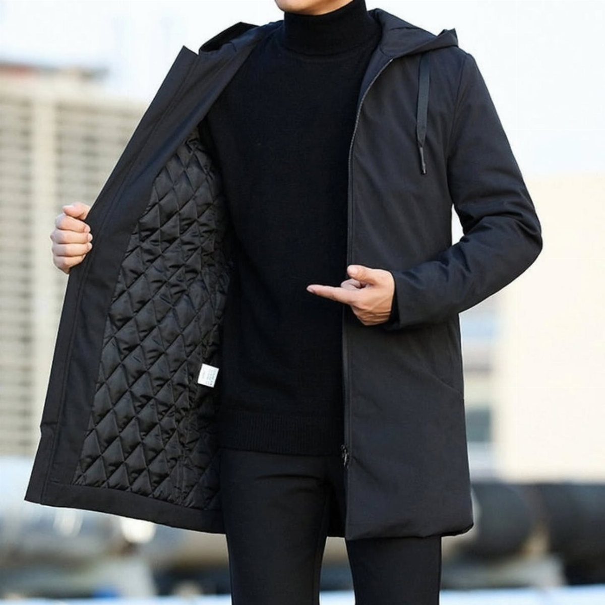 Man wearing a black hooded parka with a quilted diamond-pattern inner lining.