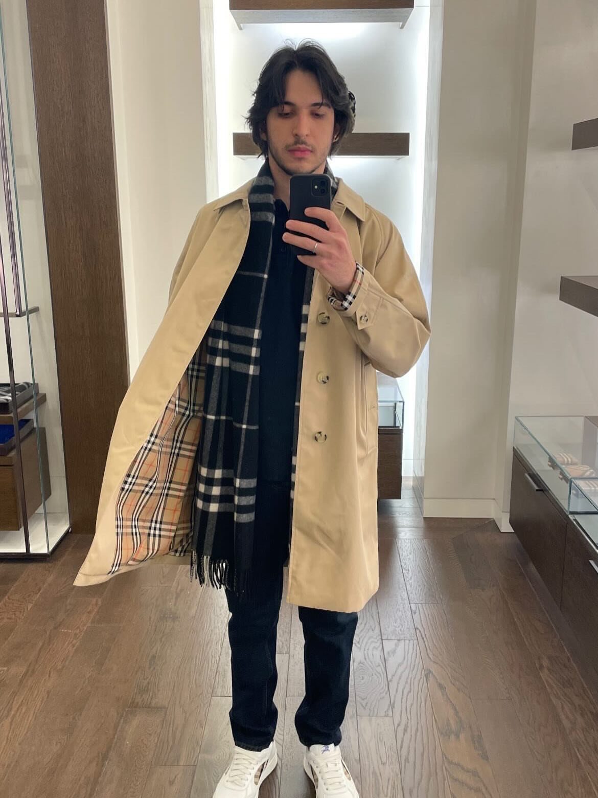 Man wearing a beige Burberry trench coat with plaid lining and matching scarf.