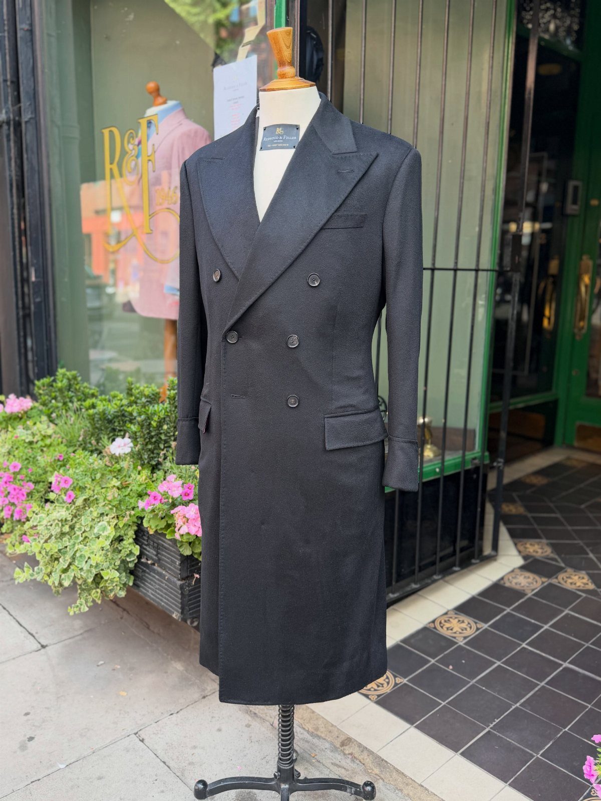 Charcoal grey double-breasted wool coat on a mannequin outside a storefront.