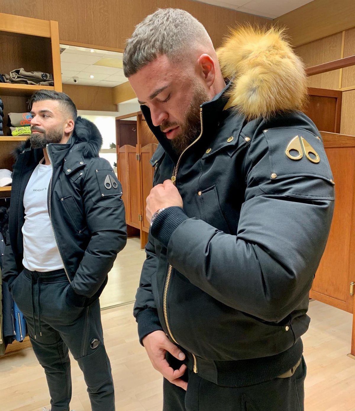 Man wearing a black hooded parka with fur trim in a clothing store