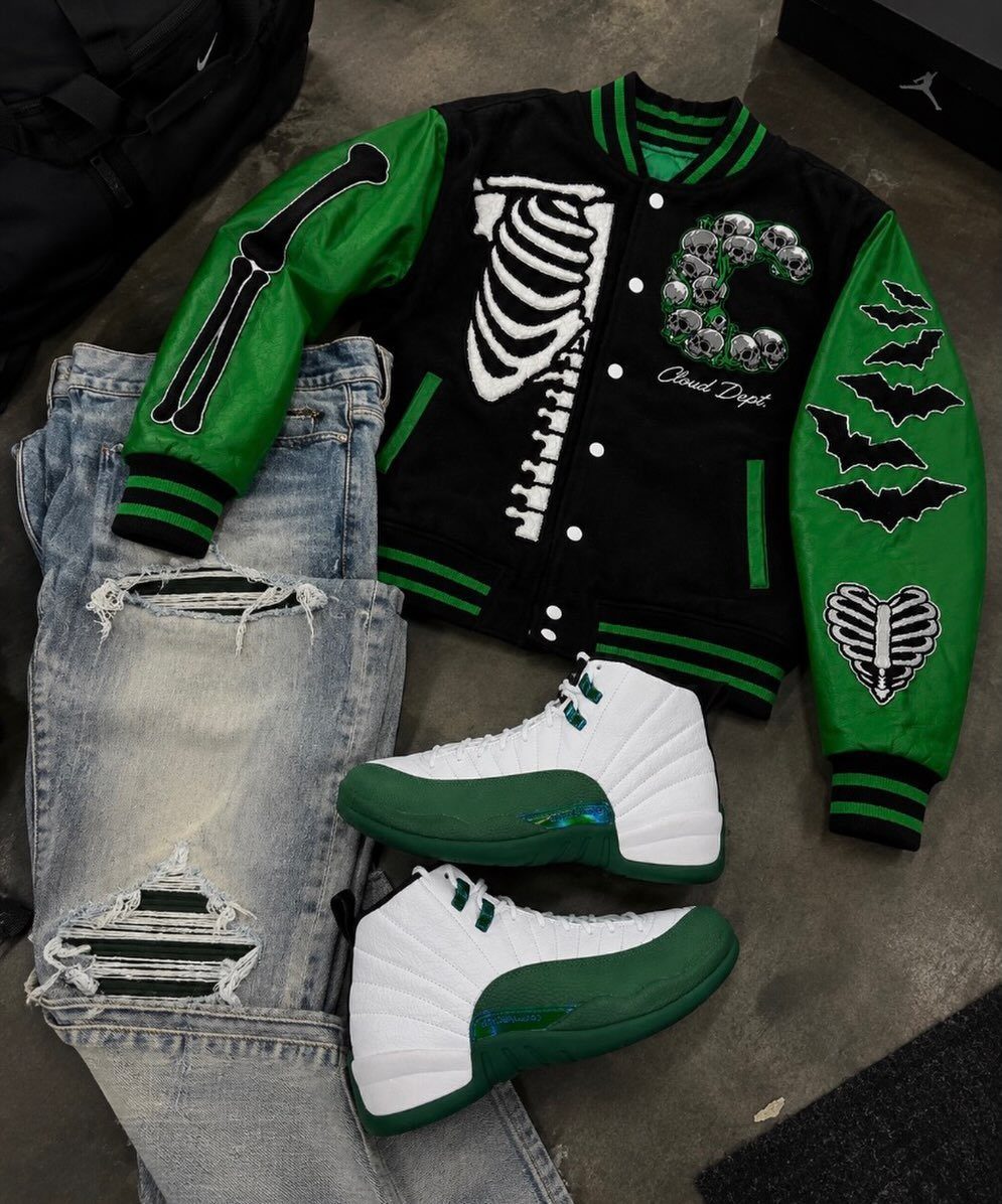 Black and green varsity jacket with skeleton graphics, ripped jeans, and white sneakers.