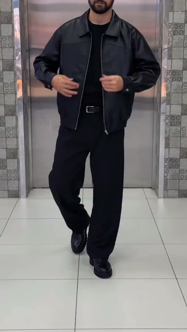 Man wearing an all-black outfit featuring a leather jacket and black trousers.