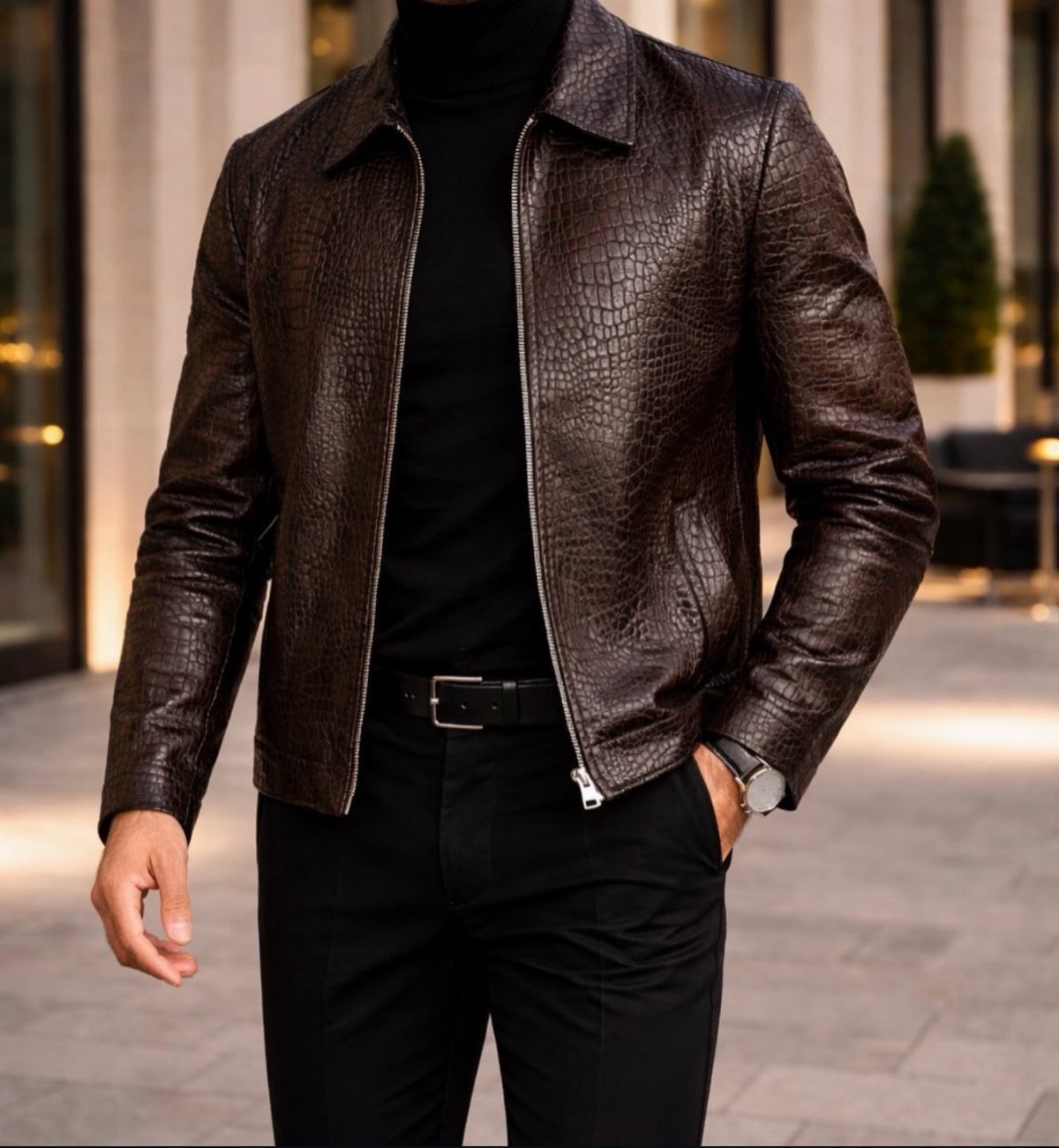 Man wearing a brown crocodile-embossed leather jacket over a black turtleneck and trousers.