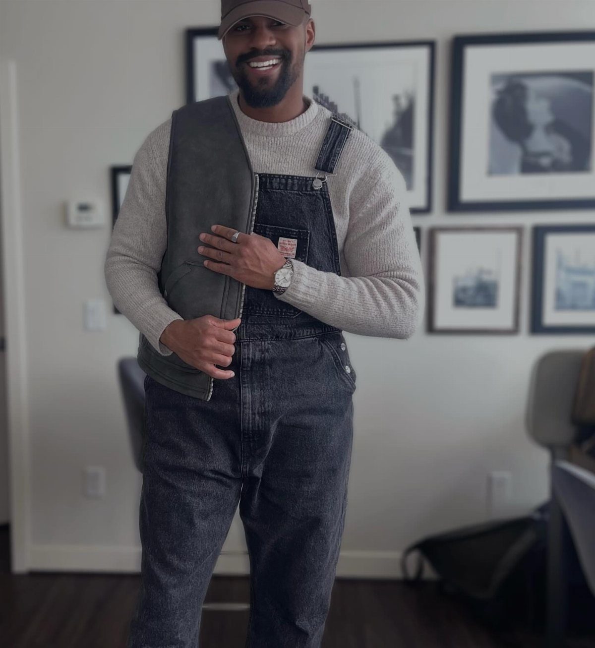 Man in dark grey denim overalls and grey sweater wearing a silver watch