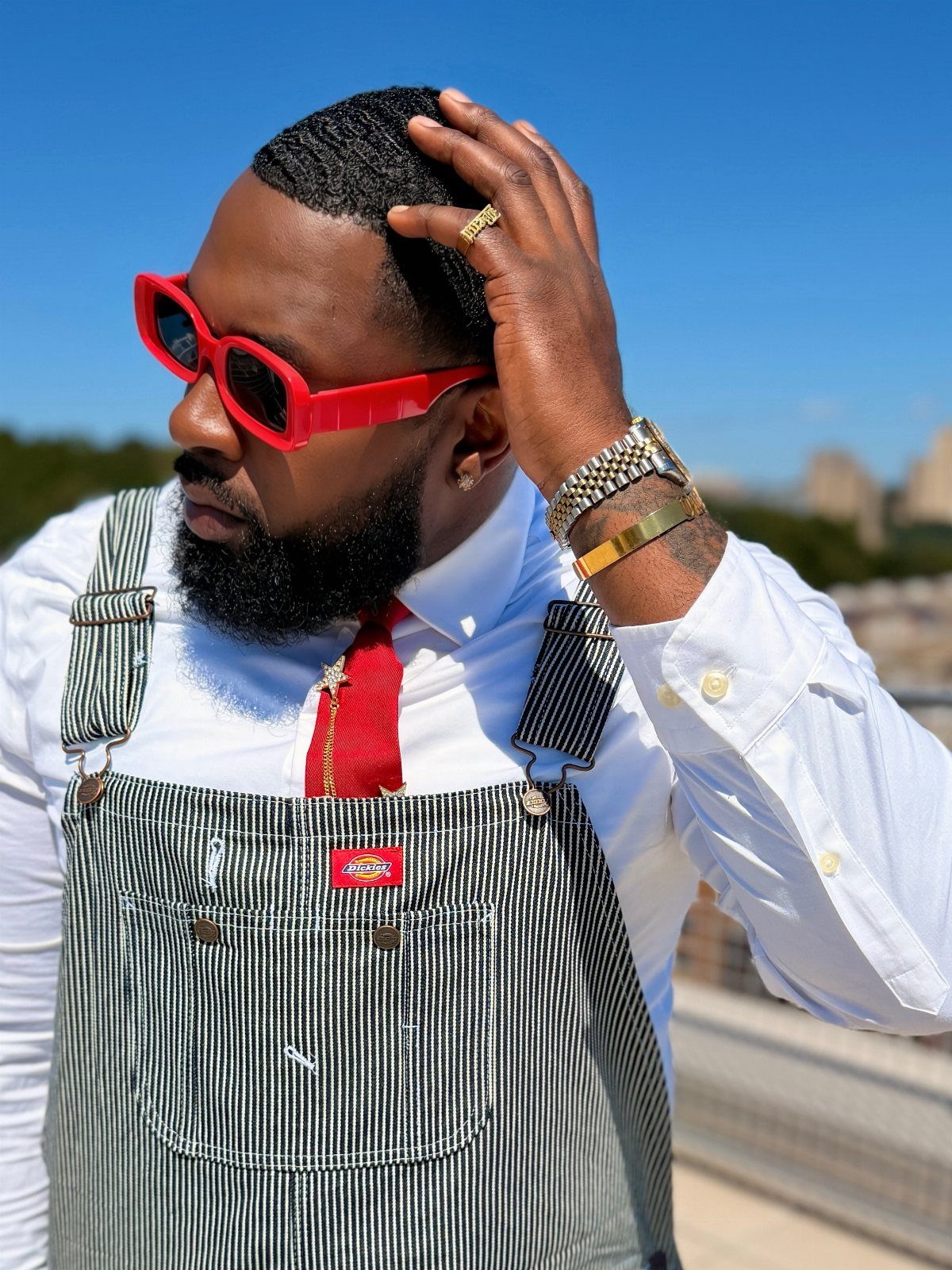 Man in pinstriped black overalls, white button-up shirt, red tie, and red sunglasses.