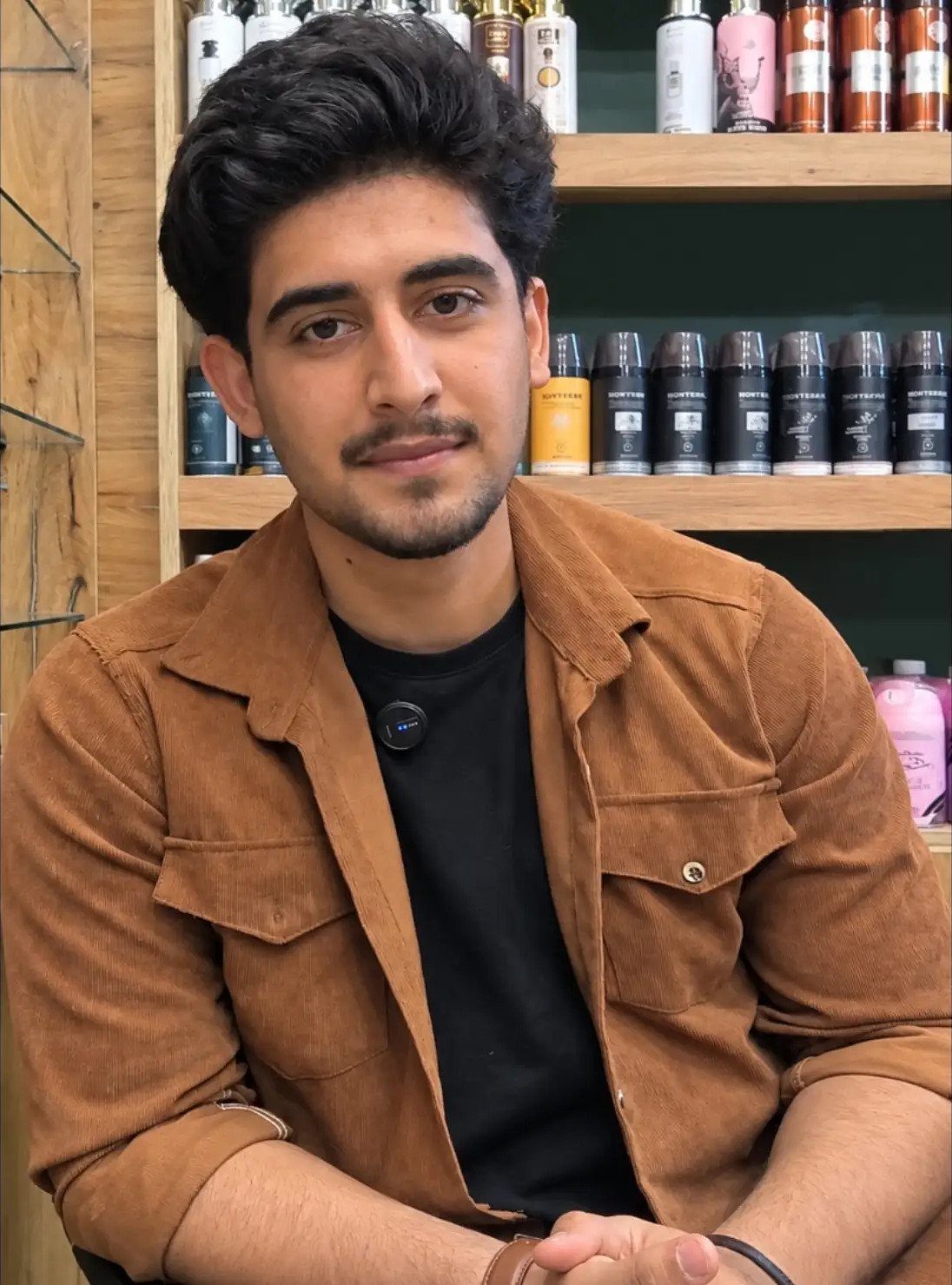 Man wearing a brown corduroy overshirt and black t-shirt in a grooming shop