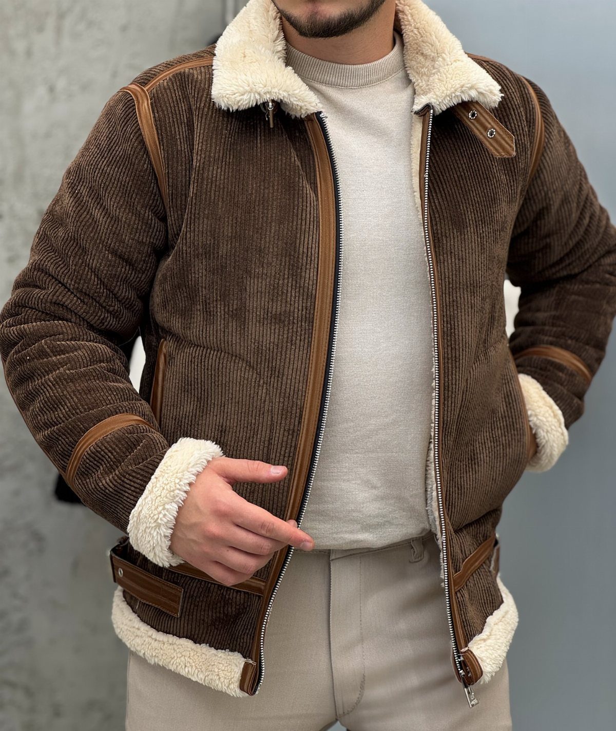 Brown corduroy jacket with white shearling lining worn over a beige sweater.