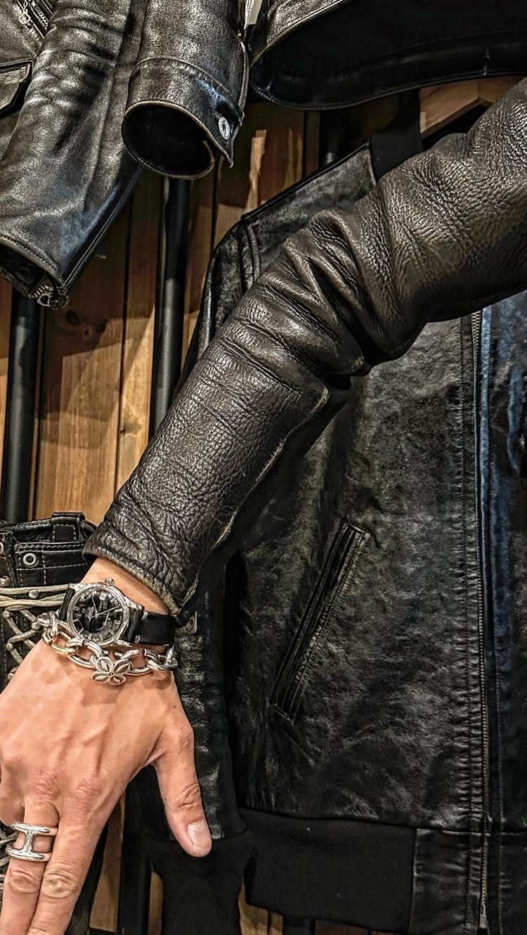 Black leather jacket sleeve with a silver bracelet, watch, and silver ring.