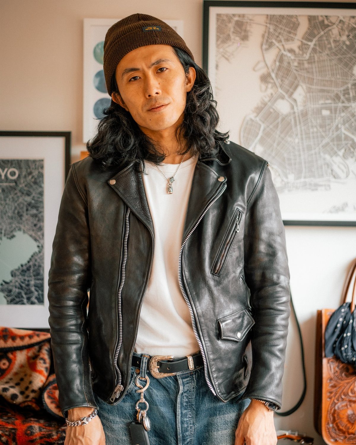 Man wearing a black leather biker jacket with a beanie and silver jewelry.