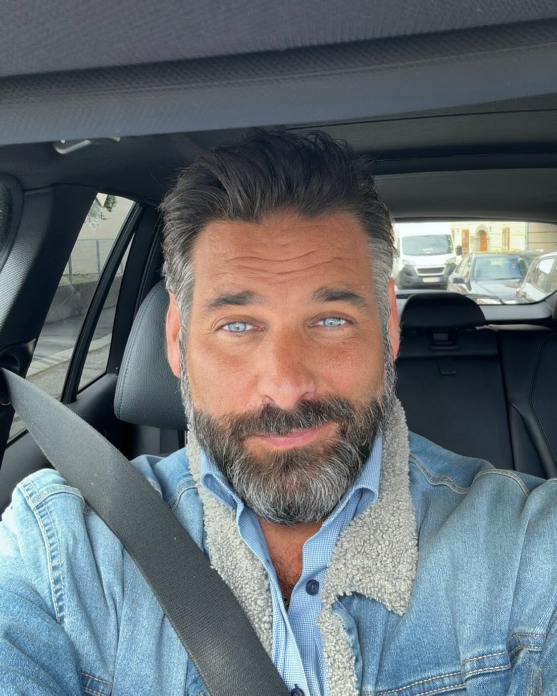 Man with beard wearing a sherpa-lined denim jacket and blue button-down shirt.