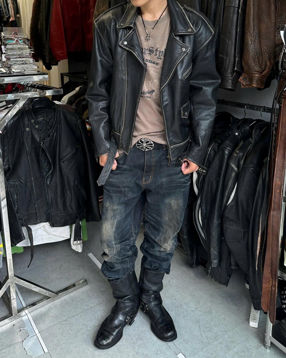 Person wearing a black leather double rider jacket, blue jeans, and black boots.