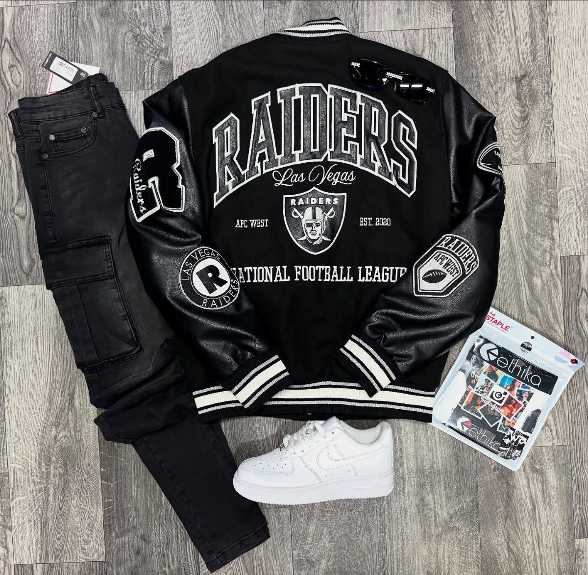 Black leather Raiders varsity jacket paired with black jeans and white sneakers.