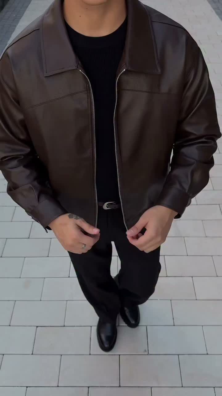 Person wearing a dark brown leather jacket with black t-shirt and trousers.