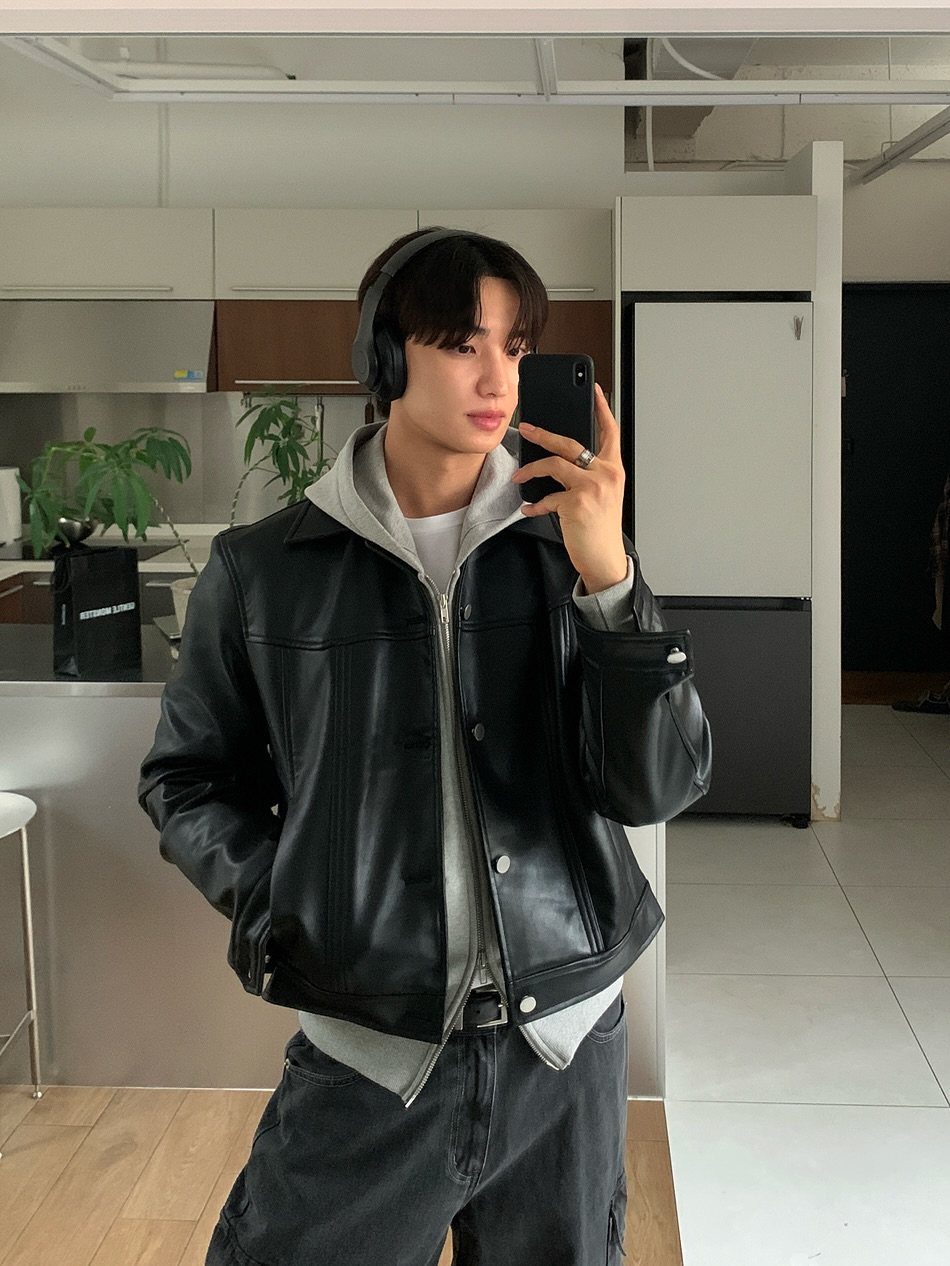 Young man wearing a black leather jacket over a grey hoodie and headphones.