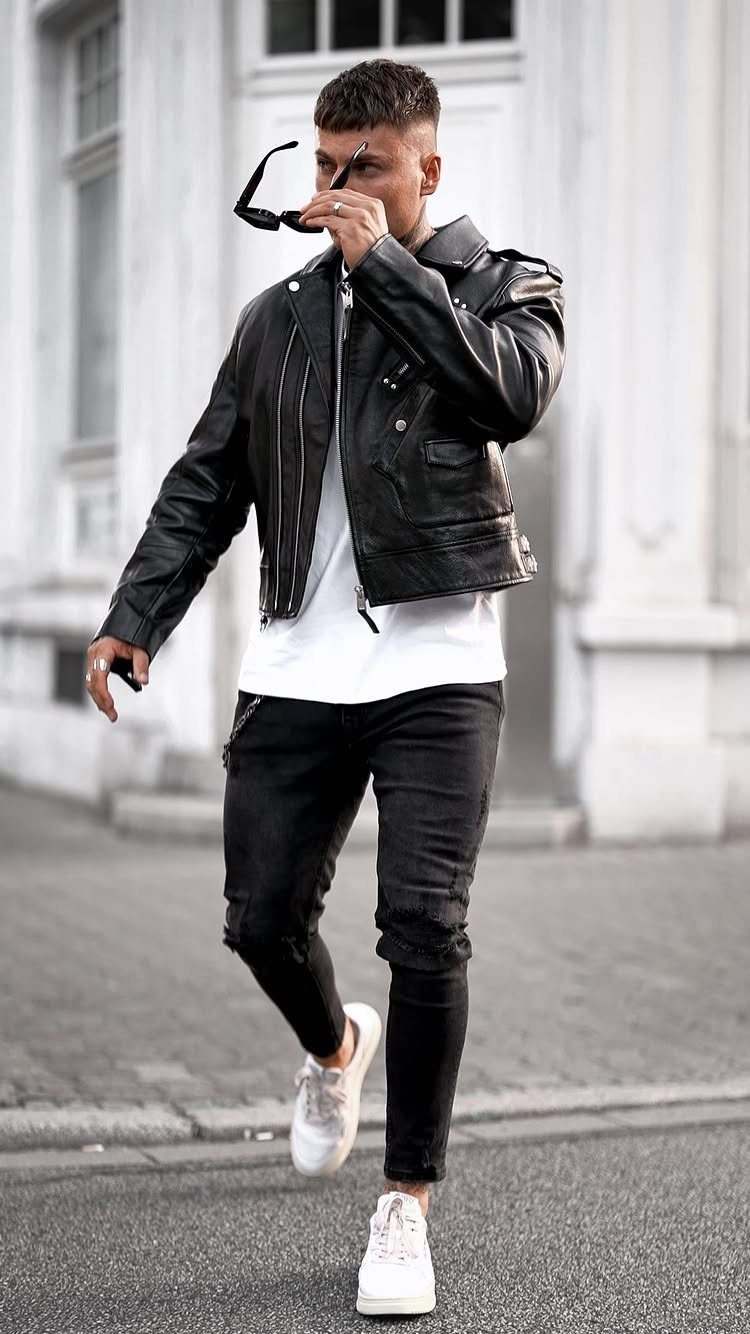 Man in black leather jacket, white t-shirt, and black jeans on city street