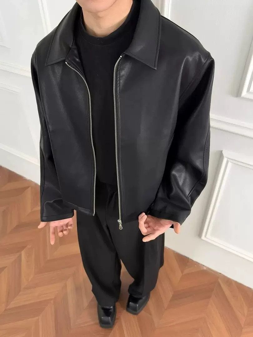 Black leather jacket ending at the waist worn with black pants and shirt.